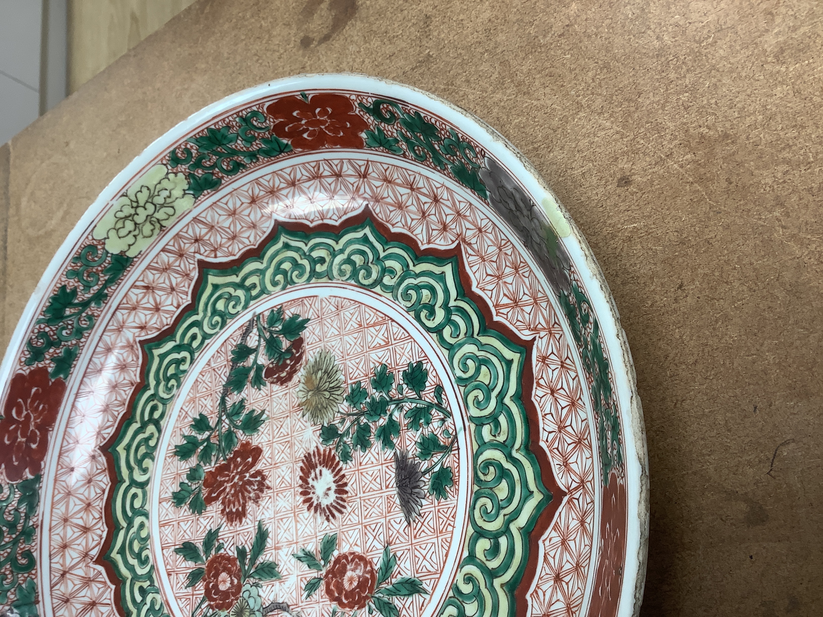 A Chinese famille verte dish, Kangxi period, decorated with flowers bands of brocade patterns, channel moulded foot, 33cm diameter